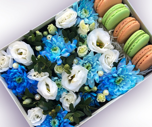 Синяя хризантема, белая эустома и макаруны в прямоугольной коробке с декором