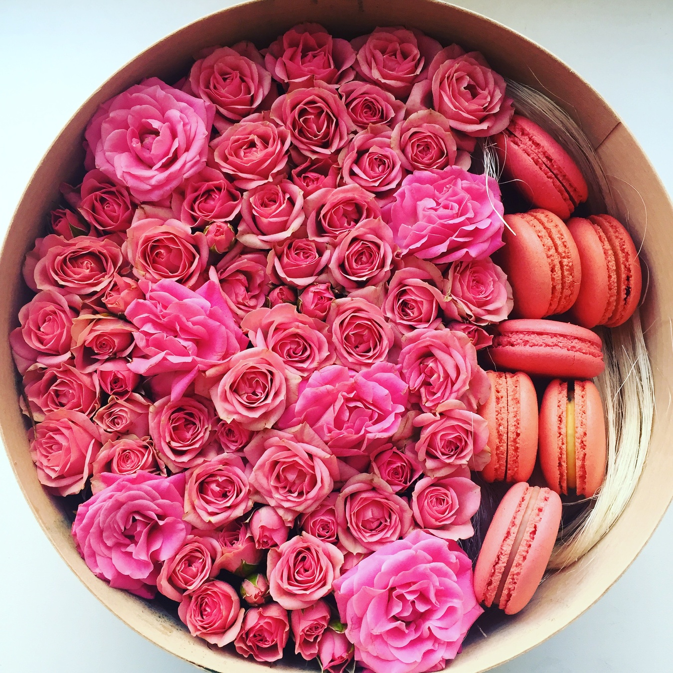 Кругла коробка трояндами в ніжних рожевих тонах і макарунами